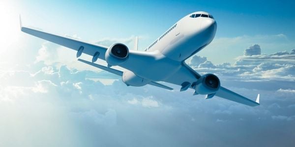 A white aircraft is flying above clouds.