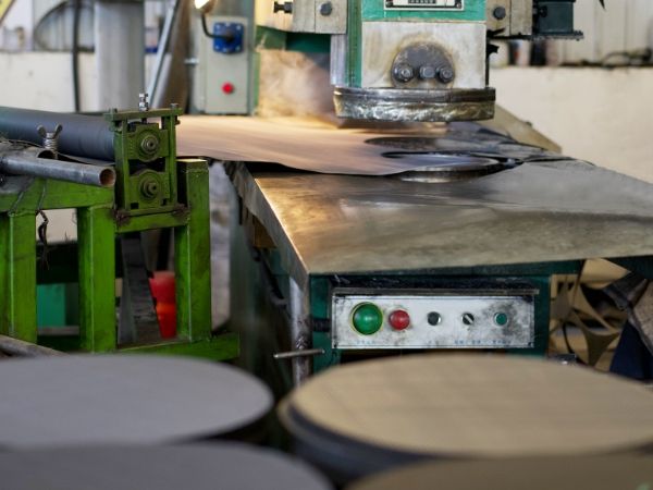 The worker is using the punching machine to produce round woven mesh.