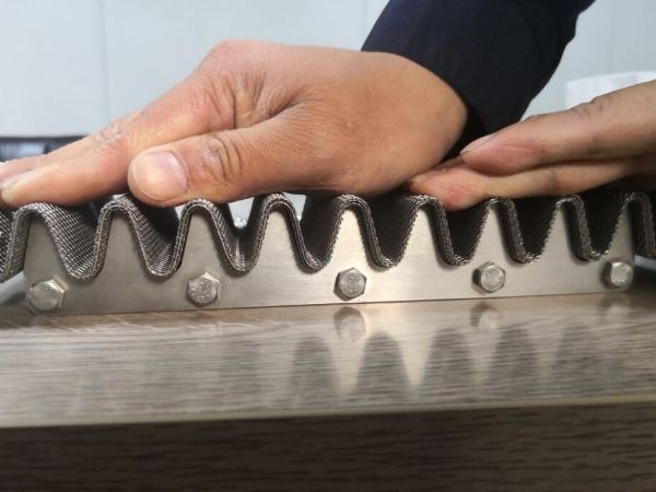 The worker is pressing the woven mesh onto the pleating machine.